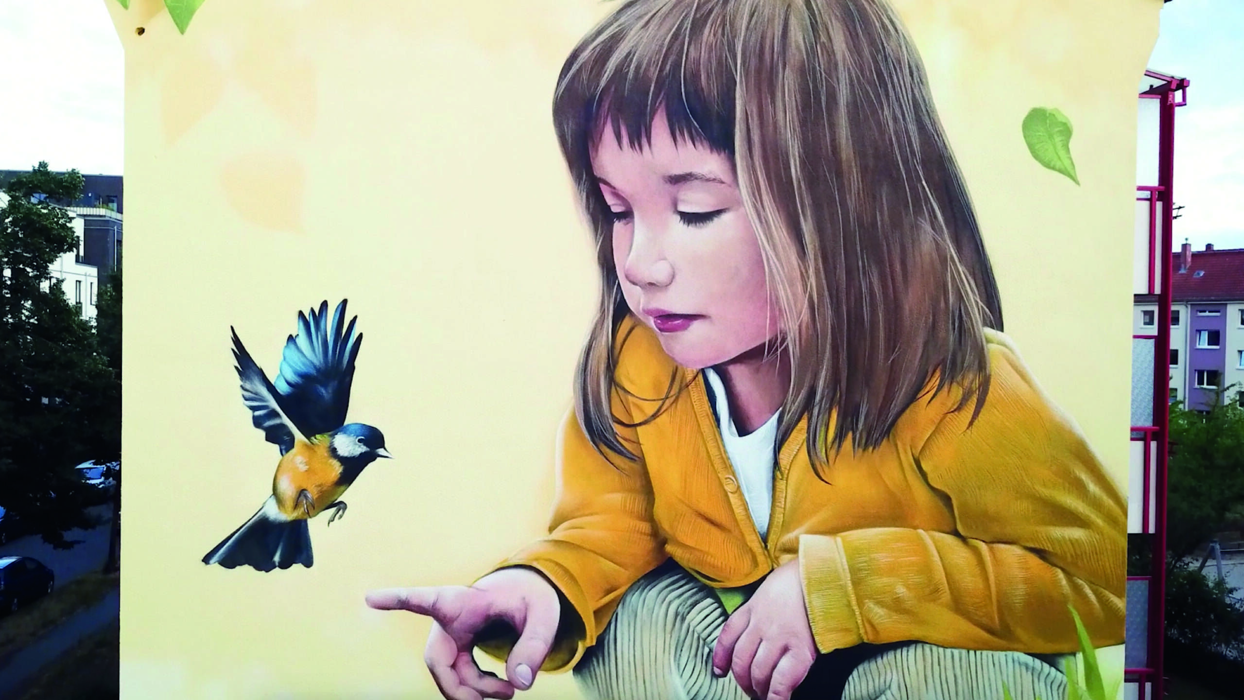 Fassadengestaltung Berlin_ Demut, Die Unschuld, Deutsche Wohnen copyright Million Motions Fassadengestaltung Berlin_ man sieht eine große Fassadengestaltung mit dem Motiv eines realistisch gestalteten Maedchens, das einen Vogel auf ihrem Finger begrueßt